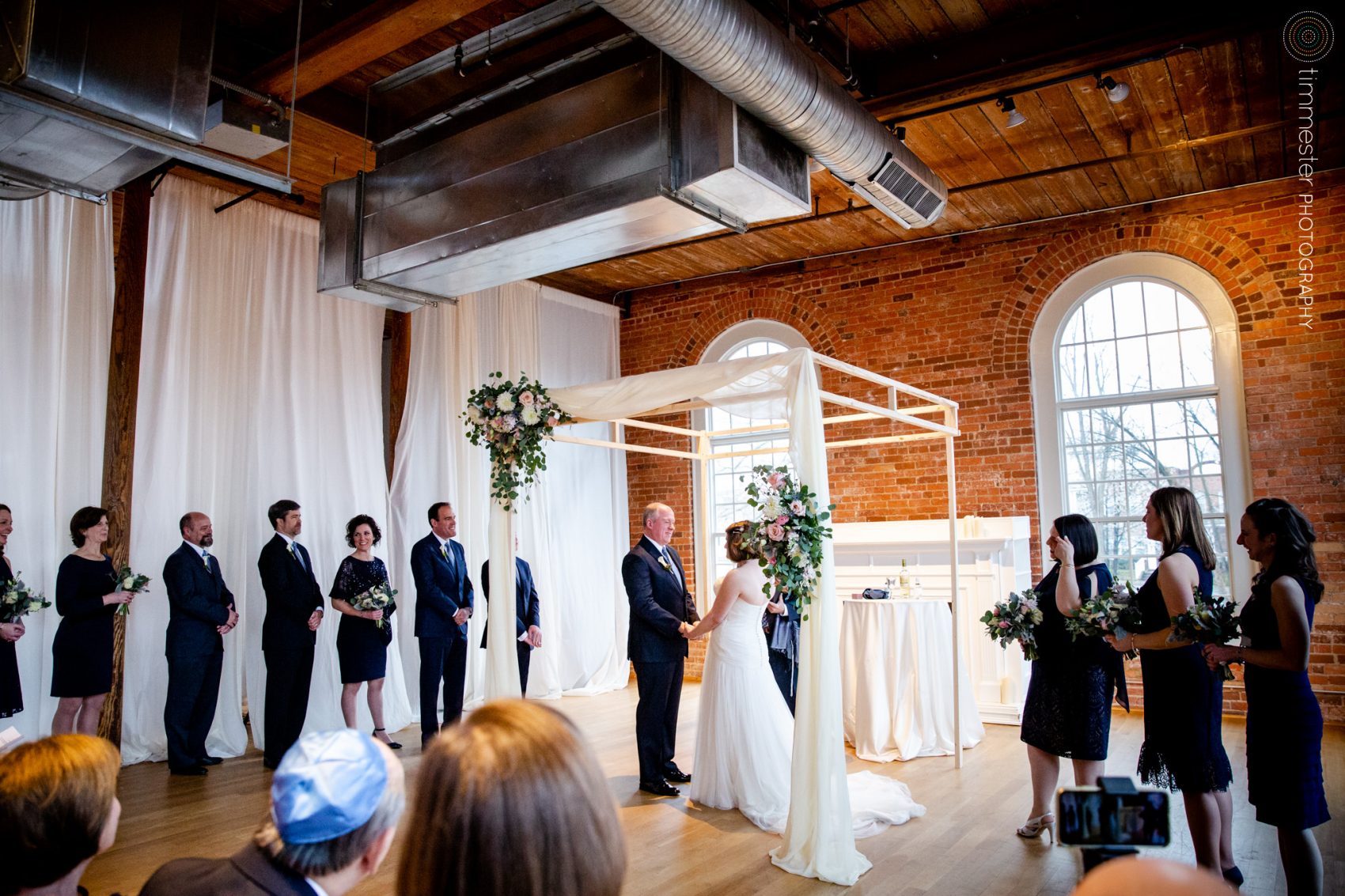 The gorgeous indoor ceremony for Jessica + David's winter wedding at The Cotton Room in NC.