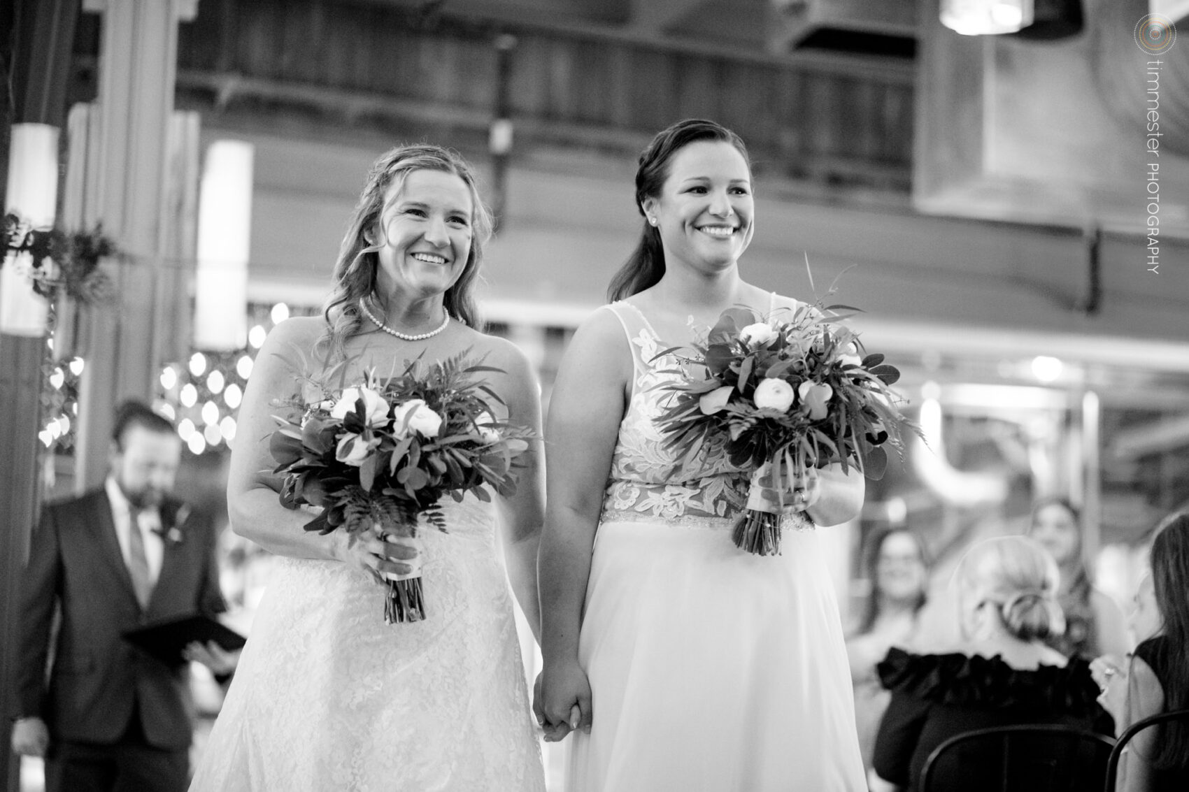 An indoor wedding ceremony with two brides at The Rickhouse in Durham, NC